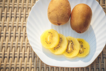 Golden kiwi fruit on white plate wicker background