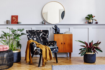 Stylish interior of living room with design armchair, wooden vintage commode, round mirror, shelf,...
