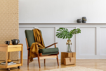 Minimalistic composition at living room interior with design green armchair, beige panel, plants, carpet, shelf, copy space, decoration and elegant personal accessories in stylish home decor.