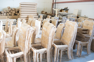 a large number of wooden chairs in a warehouse for furniture production
