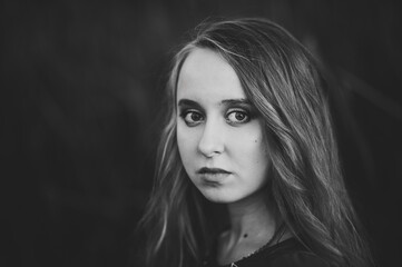 Fototapeta premium Portrait of a beautiful girl in autumn against the background of the field on the nature..Black and white photo.