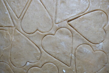 Heart shaped cookie cutters cutting out holiday cookies.