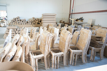 a large number of wooden chairs in a warehouse for furniture production