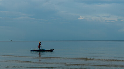 Fototapeta na wymiar Older man fishing on smal boat in calm seas on the Gulf of Thailand