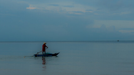 Fototapeta na wymiar Older man fishing on smal boat in calm seas on the Gulf of Thailand