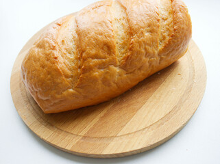loaf of white bread on a wooden board, on a light background. . The texture of the bread, homemade cakes, cooking, breakfast, bakery. Carbohydrate rejection