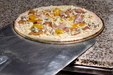 Pizza on a shovel will be fried in the oven. The process of making Italian pizza in a restaurant.