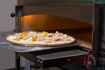Pizza on a shovel will be fried in the oven. The process of making Italian pizza in a restaurant.