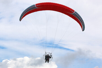 Paramotor pilot flying in a blue sky	