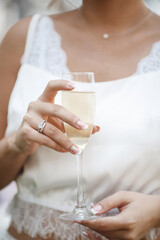 wedding and engagment ring on hand with champagne. woman's hand with glass of sparkling wine - 358540651