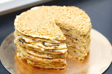 layer cake with cream, sprinkled with crumbs on a black table. one piece of the pie has already been cut off