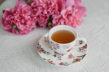 pink peonies on the table with a cup of tea