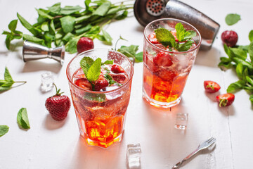 Strawberry mojito and ingredients on white wooden background