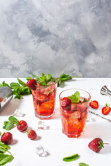 Strawberry mojito and ingredients on white wooden background