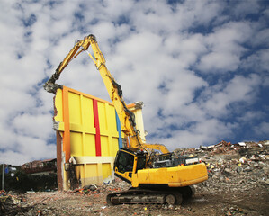 a high reach demolition excavator demolishing building. a big excavator working demolishing site. 