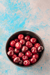 fresh cherry fruits in bowl on gray background with copy space