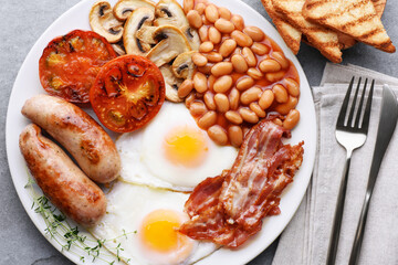 English breakfast on a plate. Grilled sausages, bacon, eggs, mushrooms, tomatoes and beans.
