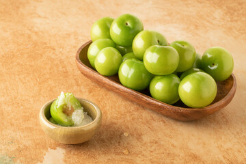 closeup fresh and ripe green plums on a table served with salt