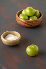 closeup fresh and ripe green plums on a table served with salt