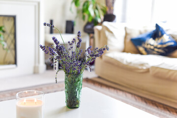 Modern home interior of living room with scented candle and lavender flowers on coffee table