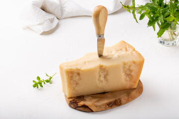 Piece of parmesan cheese on  wooden board on white background. Parmigiano Reggiano, hard mature...