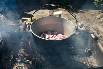 Roasting pork in cauldron on coals