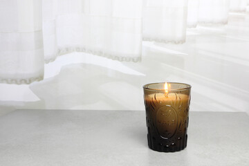 The luxury lighting aromatic scent glass candle diplay on the grey table in the white bedroom with background of the curtain