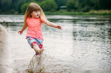 Little cute girl has fun playing with a spray of water in the sea. The baby is laughing. The concept of rest. Selective focus image. copy space