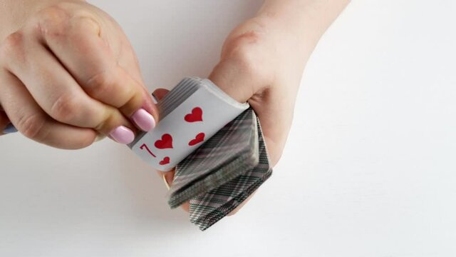 Women's Hands Shuffling A Deck Of Cards.Playing On A White Table.