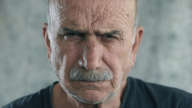 Angry old man portrait. Face of elderly senior guy, serious face looking to camera, close up face portrait.