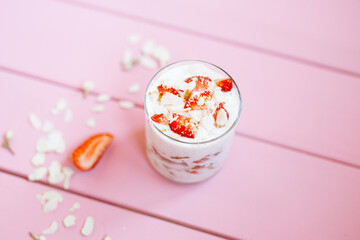 layered summer dessert with strawberries, sponge cake and yogurt on a pink tree background.