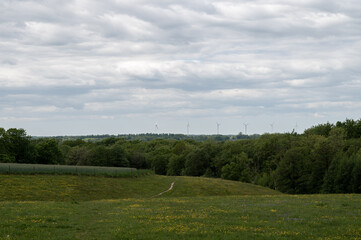 A row of six wind turbines rises above the lush green landscape in Skåne, Sweden