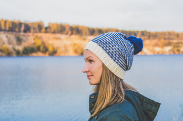 Fototapeta na wymiar Woman in a hat in the fall on the background of the lake
