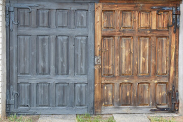 Old aged brown grey wooden garage door  need of repair and painting, half painted doors.  Home improvement, renovation and diy concept.
