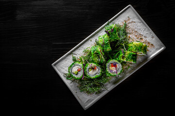 Sushi rolls with seafood and Chuka salad on black wooden table background