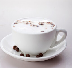 A cup of cappuccino coffee with foam and granules, decorated with coffee beans, isolated on white shades.