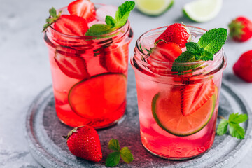 Strawberry lime lemonade with fresh mint and ice in glass jar.