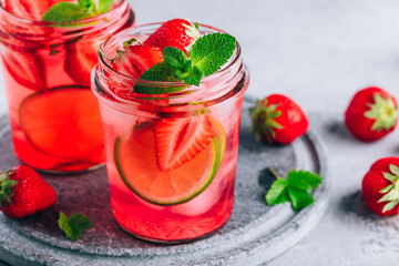 Strawberry lime mojito with fresh mint and ice in glass jar.