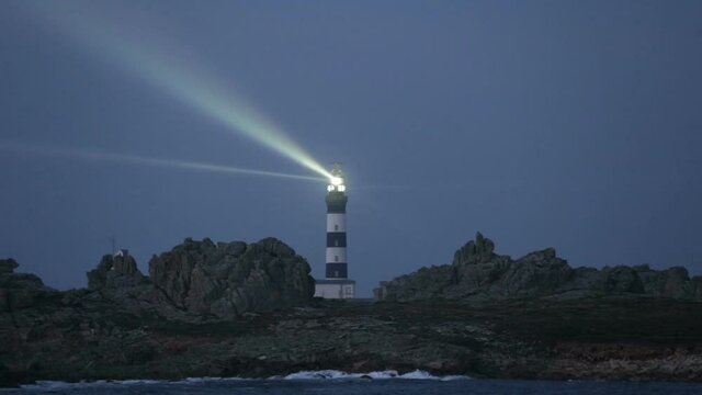 Cr&eacute;ac'h lighthouse illuminated in evening with seagulls flying over the sky, the most powerful in the world, Ushant island (aka Ouessant), Brittany, France