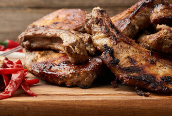 grilled pork steaks on the bone on a kitchen cutting board and red chili pepper