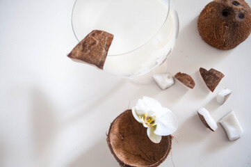 Coconut cocktail on the glass with a white background with free space. Coconut milk, chopped coconut. Flower Orchid as Scenery