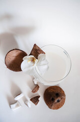 Coconut cocktail on the glass with a white background with free space. Coconut milk, chopped coconut. Flower Orchid as Scenery