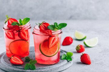 Strawberry lime mojito with fresh mint and ice in glass jar.