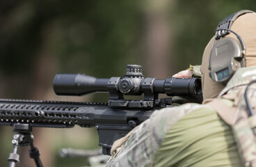 Military man in camouflage uniform with rifle.