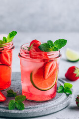 Strawberry lime mojito with fresh mint and ice in glass jar.