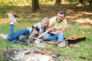 Fototapeta premium Young and beautiful couple relax in nature with a dog to the guitar