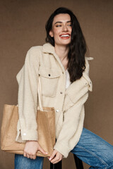 Photo of joyful woman with bag laughing while sitting on chair