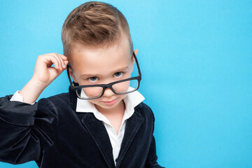 Serious little boy in glasses and suit with a piercing look from the substrate