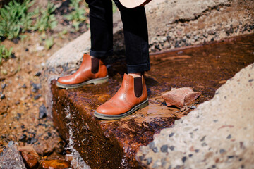 Leather shoes a man stands on a rock in the mountains near the lake groom
