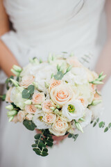 Wedding bouquet in the hands of the bride of white roses and other flowers